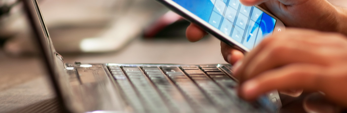 Person using mobile phone and laptop computer