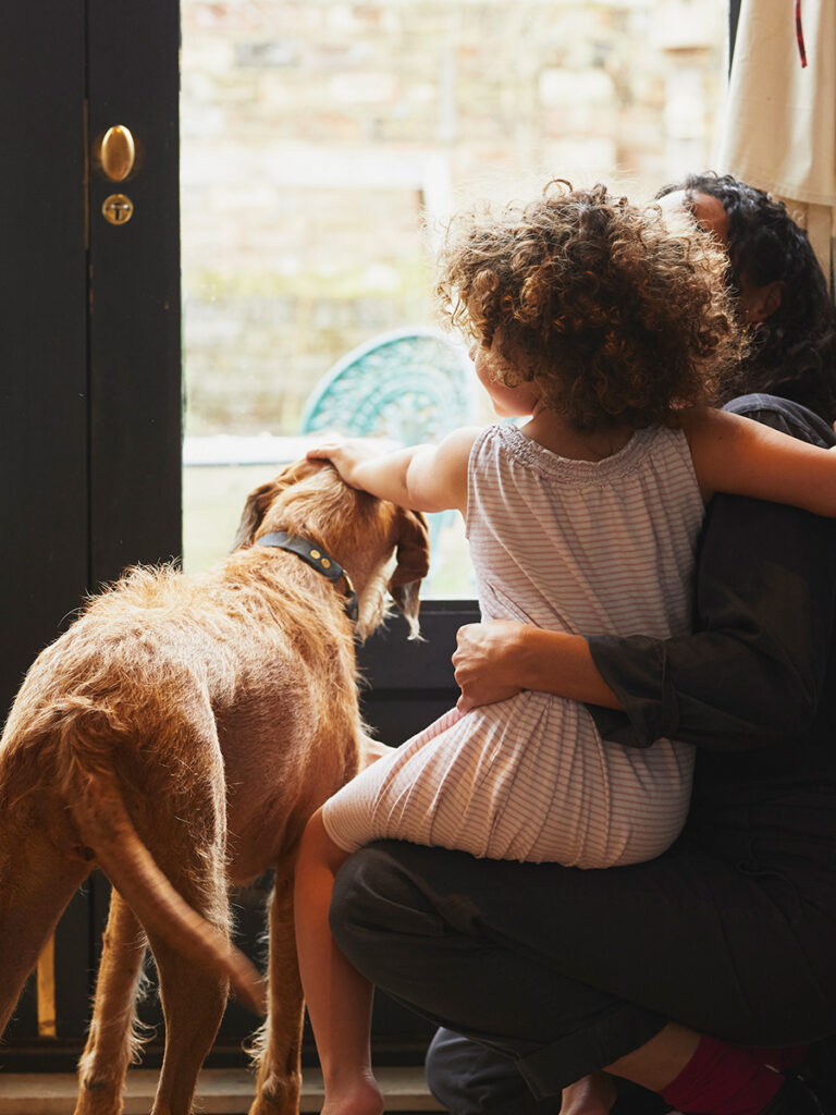 Mother, child and dog looking out the window of a door